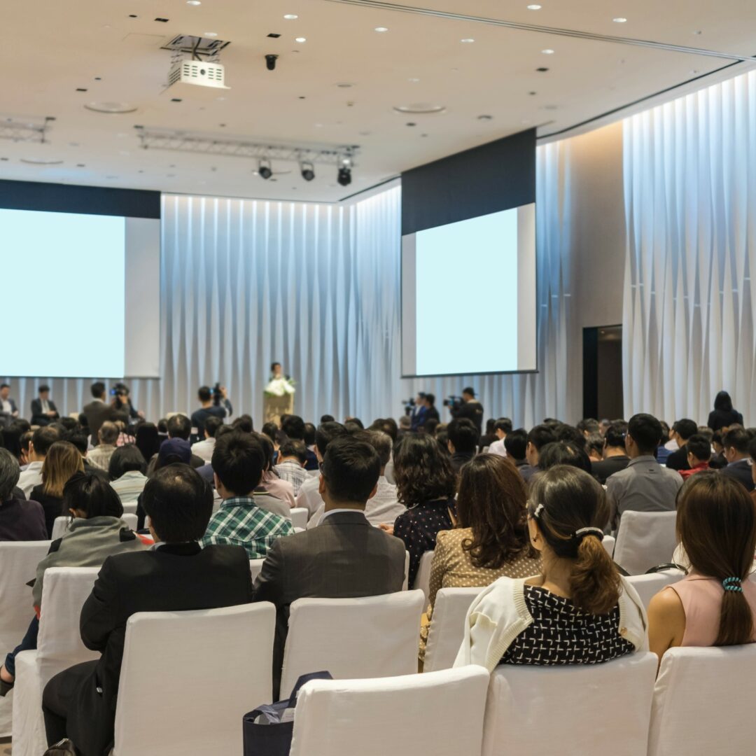 Speakers on the stage with Rear view of Audience in the conference hall or seminar meeting, business and education about investment concept